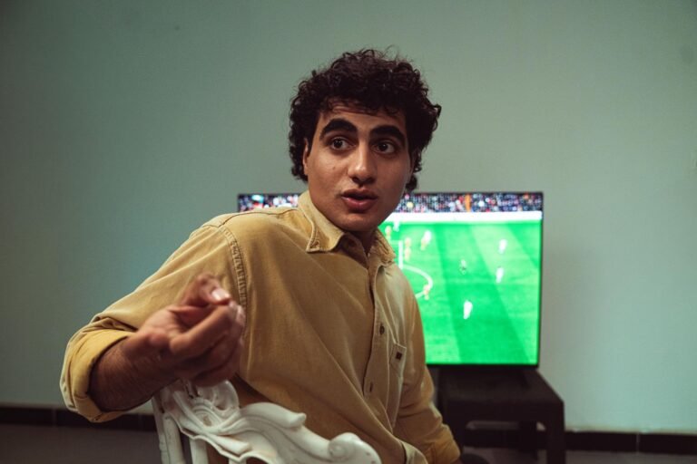 Duas ou mais telas de televisão em uma sala de estar, cada uma exibindo um jogo de futebol ao vivo, com uma sutil diferença no momento em que um gol é mostrado, indicando atraso na transmissão.