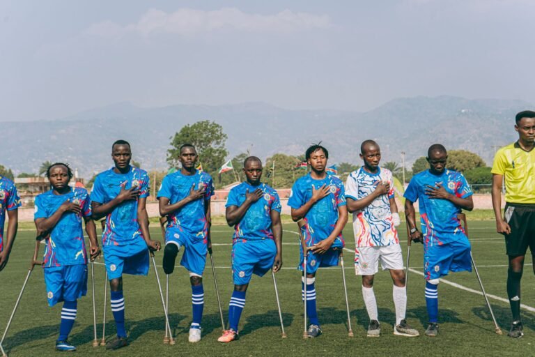 Jogadores das seleções de futebol da Escócia e do Haiti em campo, disputando a bola durante uma partida decisiva em um estádio lotado.