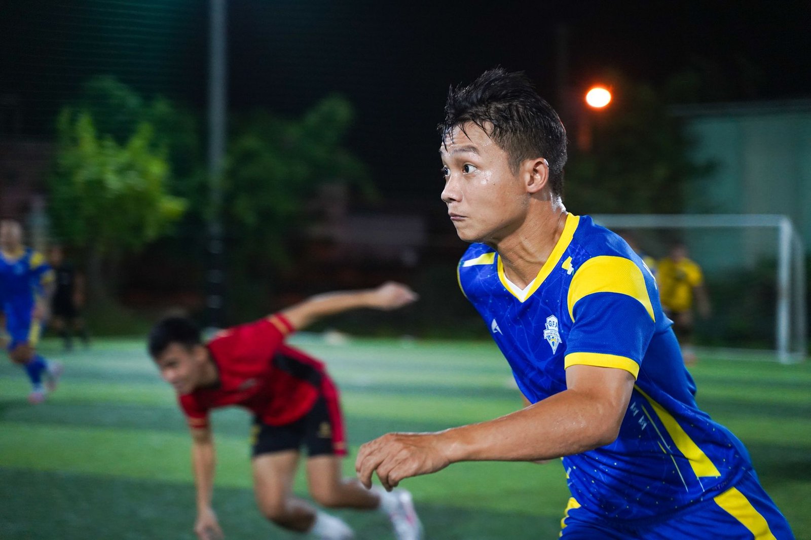 Jogador de futebol com camisa azul comemorando um gol em um estádio lotado.