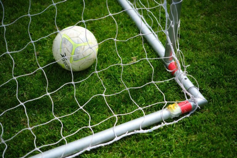 Jogador de futebol se preparando para cobrar pênalti em um estádio lotado, com goleiro pronto para defender