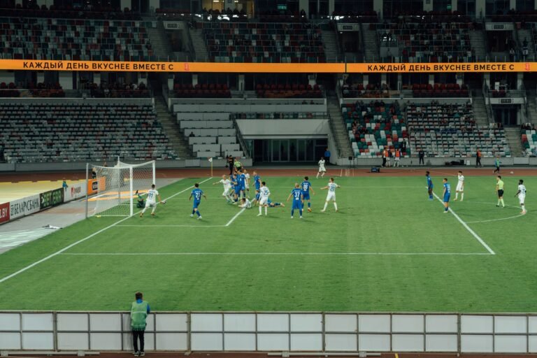 Atletas de futebol treinando em campo sintético dentro de estádio moderno