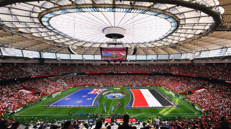 Estádio de futebol com torcida, bandeiras dos EUA e Bélgica, jogador se preparando para chutar a bola.