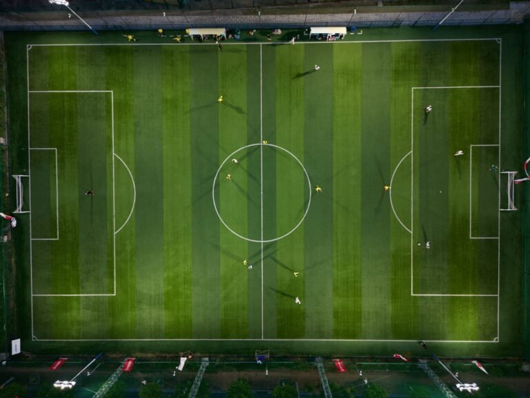 Campo de futebol com padrão de tabuleiro de xadrez no gramado, simbolizando estratégias de mercado de transferências.