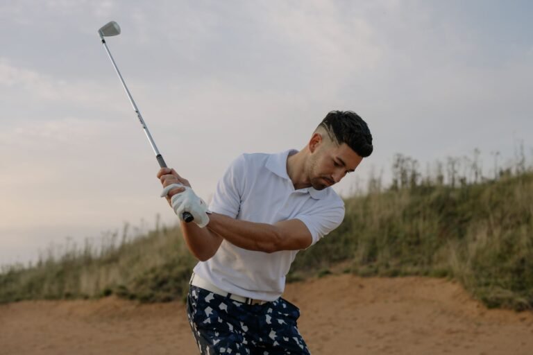 Atleta sorridente em um campo de golfe verde, segurando um taco, rodeado por fãs sob um céu ensolarado.