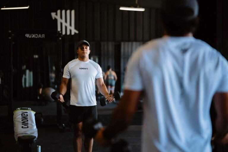 Atleta de futebol realizando um exercício de força dinâmico em uma academia moderna, com um treinador observando.
