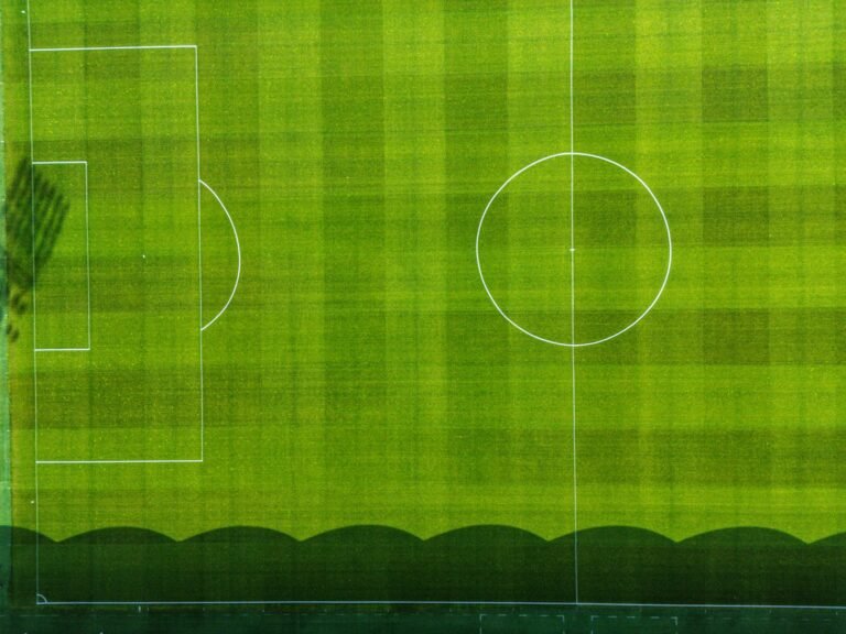 Treino de futebol com jogadores praticando no gramado e técnico explicando tática em quadro branco